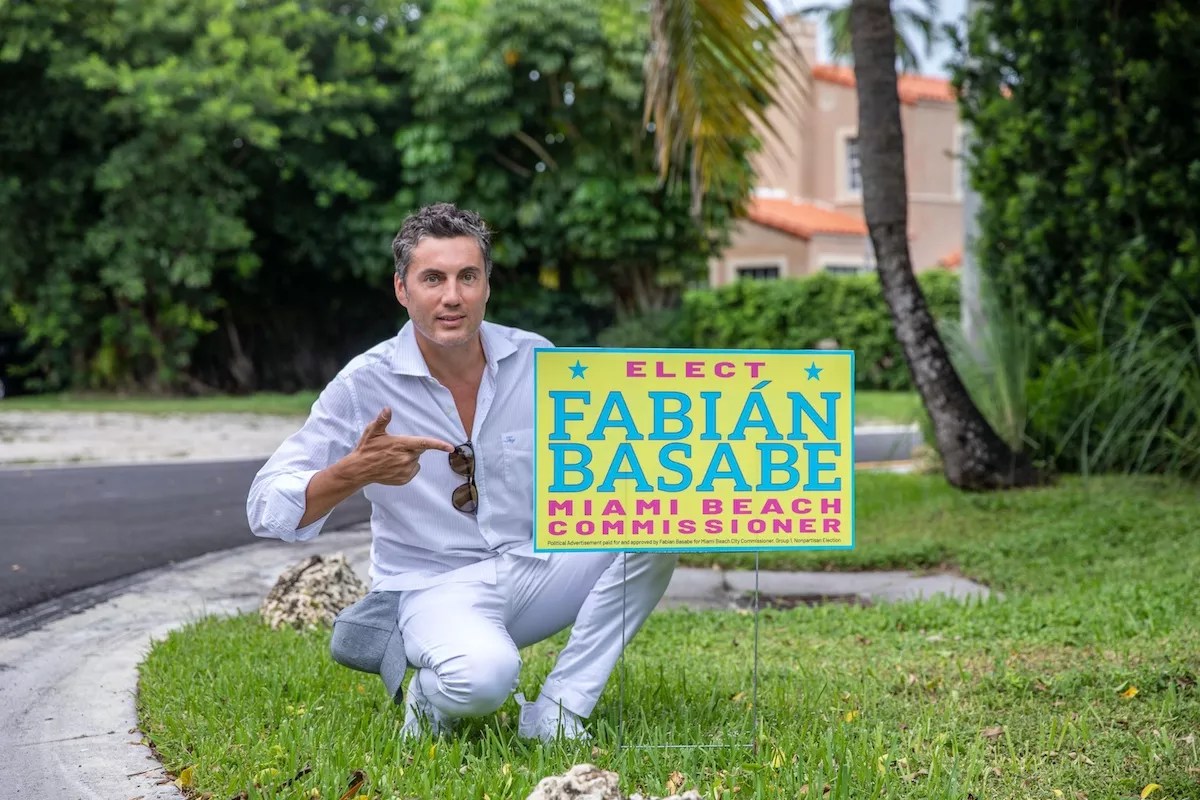 Fabian Basabe poses for photo on a lawn next to a campaign sign