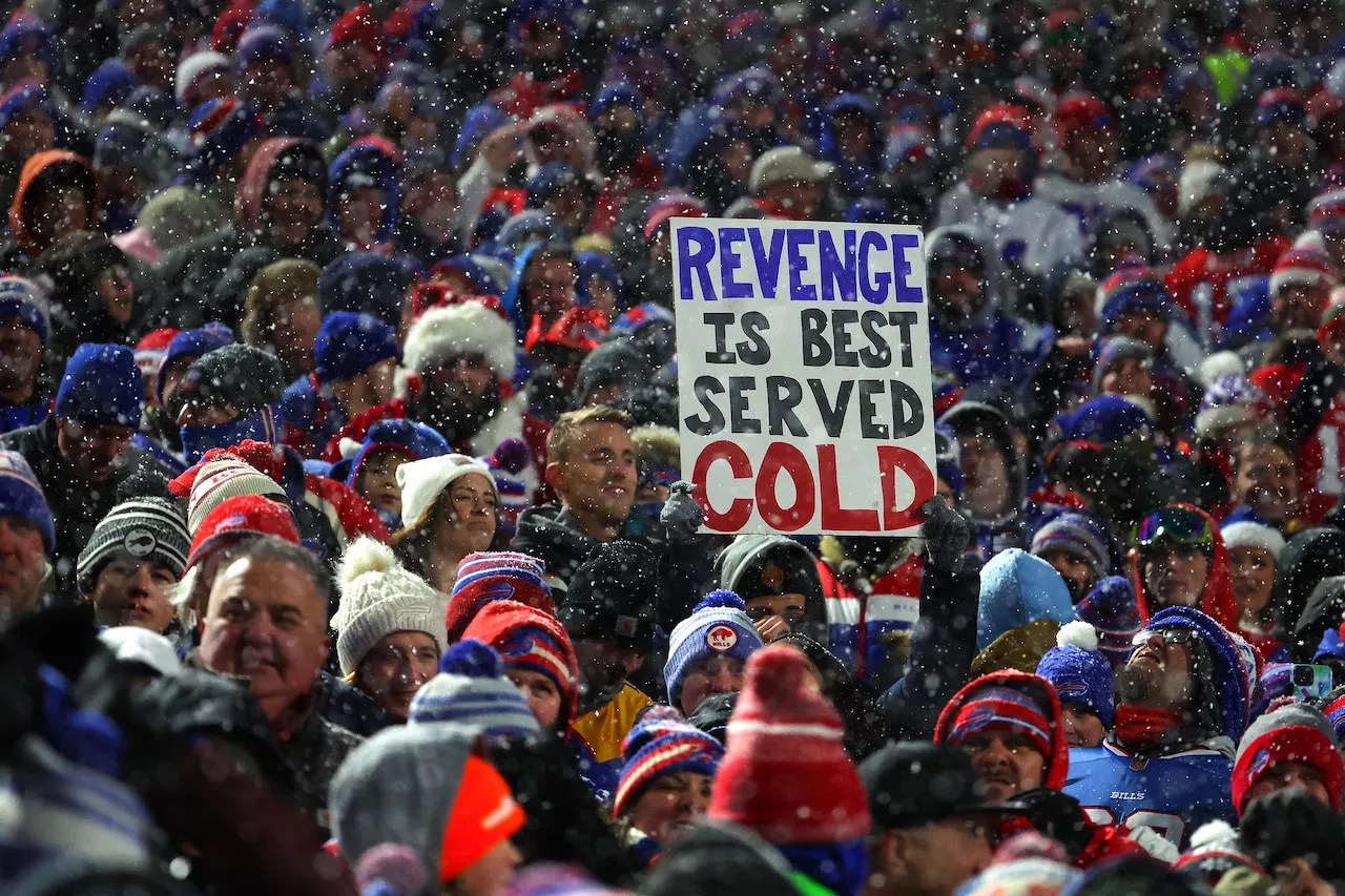 Bills fans in the snowy stands at Highmark Stadium during the December 17, 2022, 32-39 victory over the Miami Dolphins, holding up a sign that reads, "Revenge Is Best Served Cold"