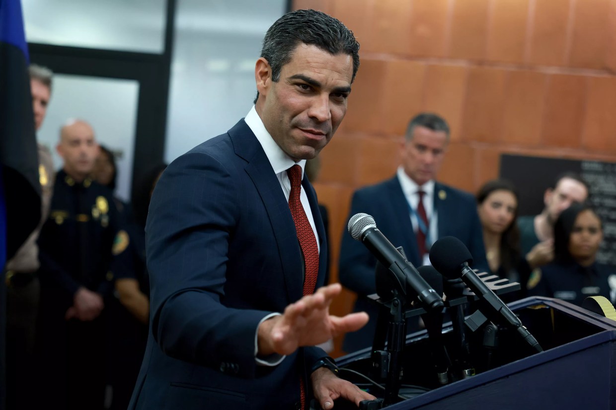 Miami Mayor Francis Suarez in a nifty suit extends an open hand in the direction of the camera