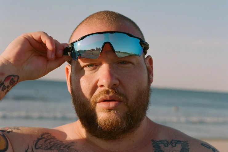 Rapper Action Bronson lifting up his sunglasses