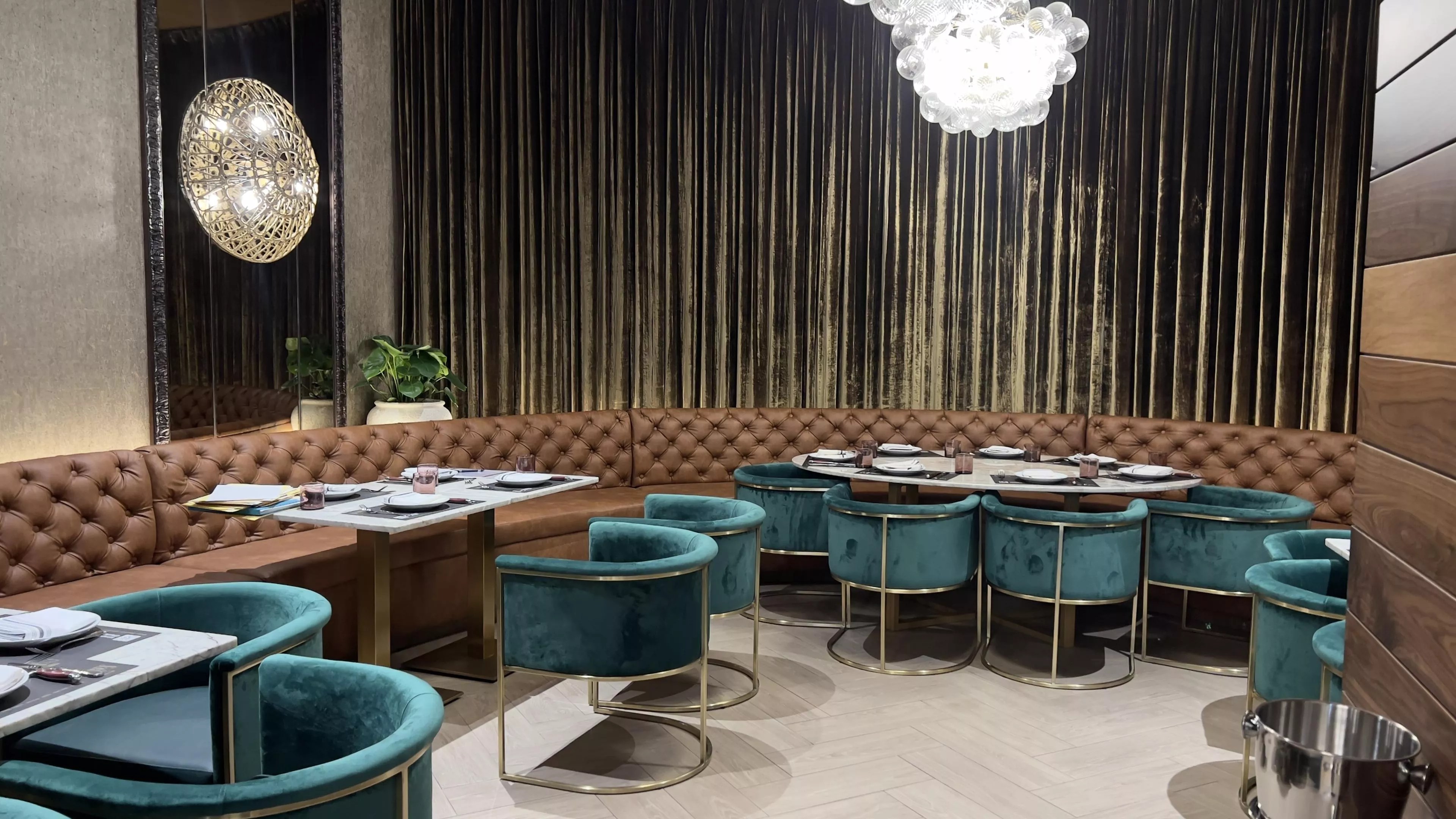 Plush teal seats fill the cozy interior dining area of Baires Grill in Downtown Doral