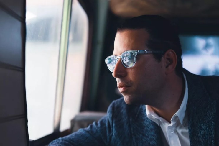 Alfredo Rodriguez, wearing sunglasses, looks out of a window