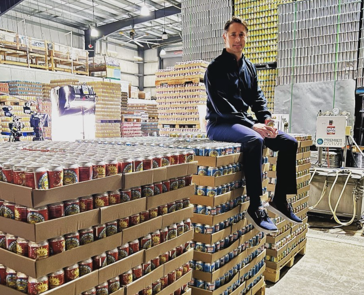 A man sits on cans of beer