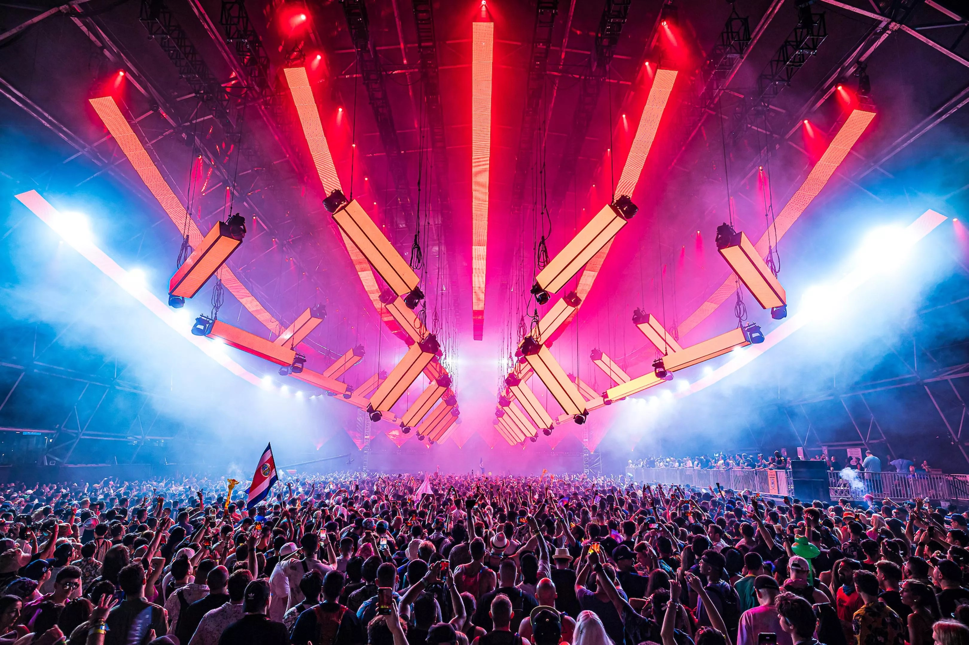 Festivalgoers dancing under massive LED lights hanging overhead