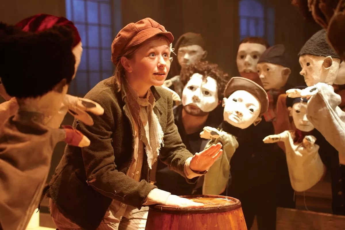 Hallie Walker on stage as Oliver singing with Fagin's boys