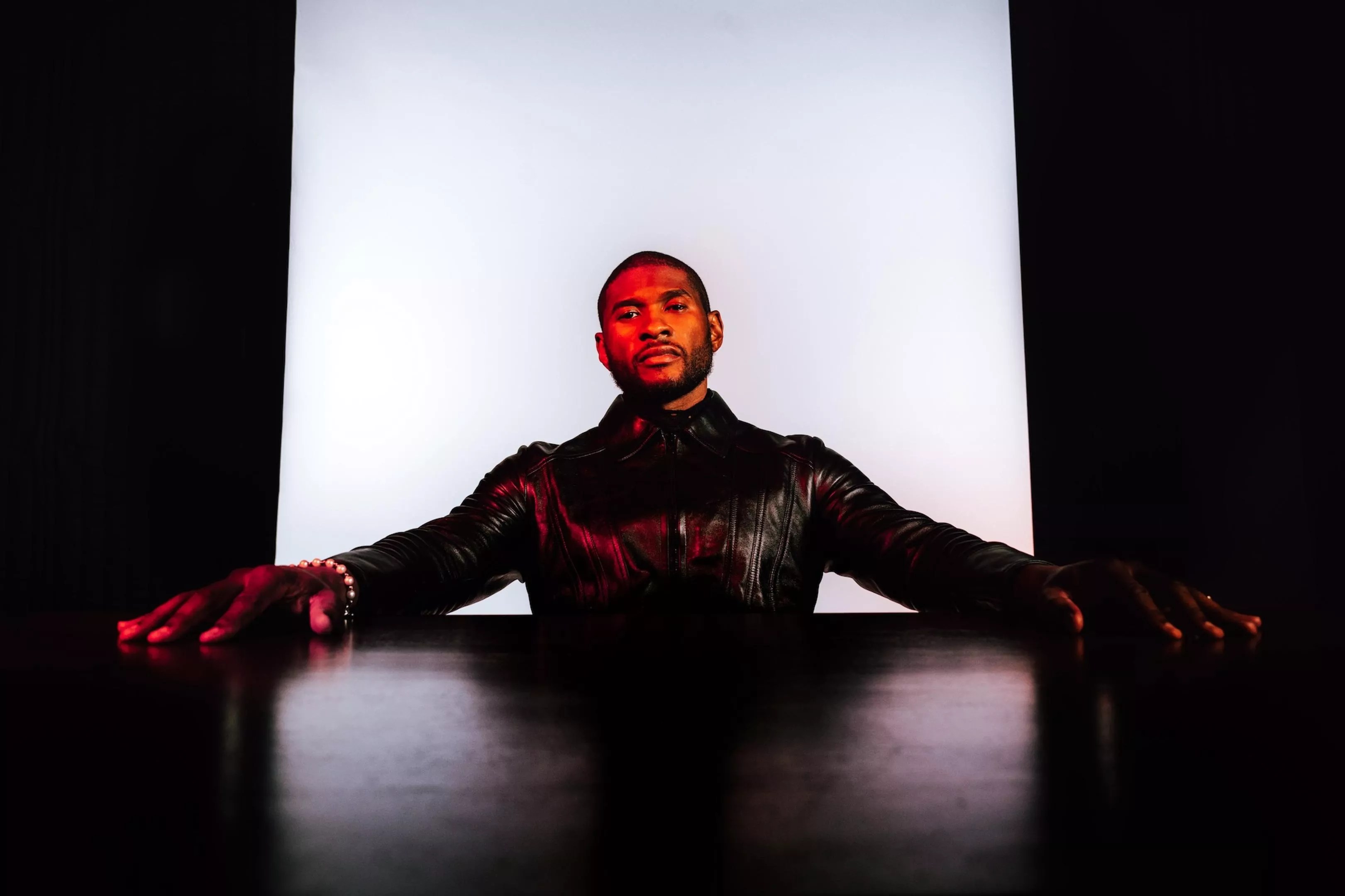 Usher with his arms stretched on a table
