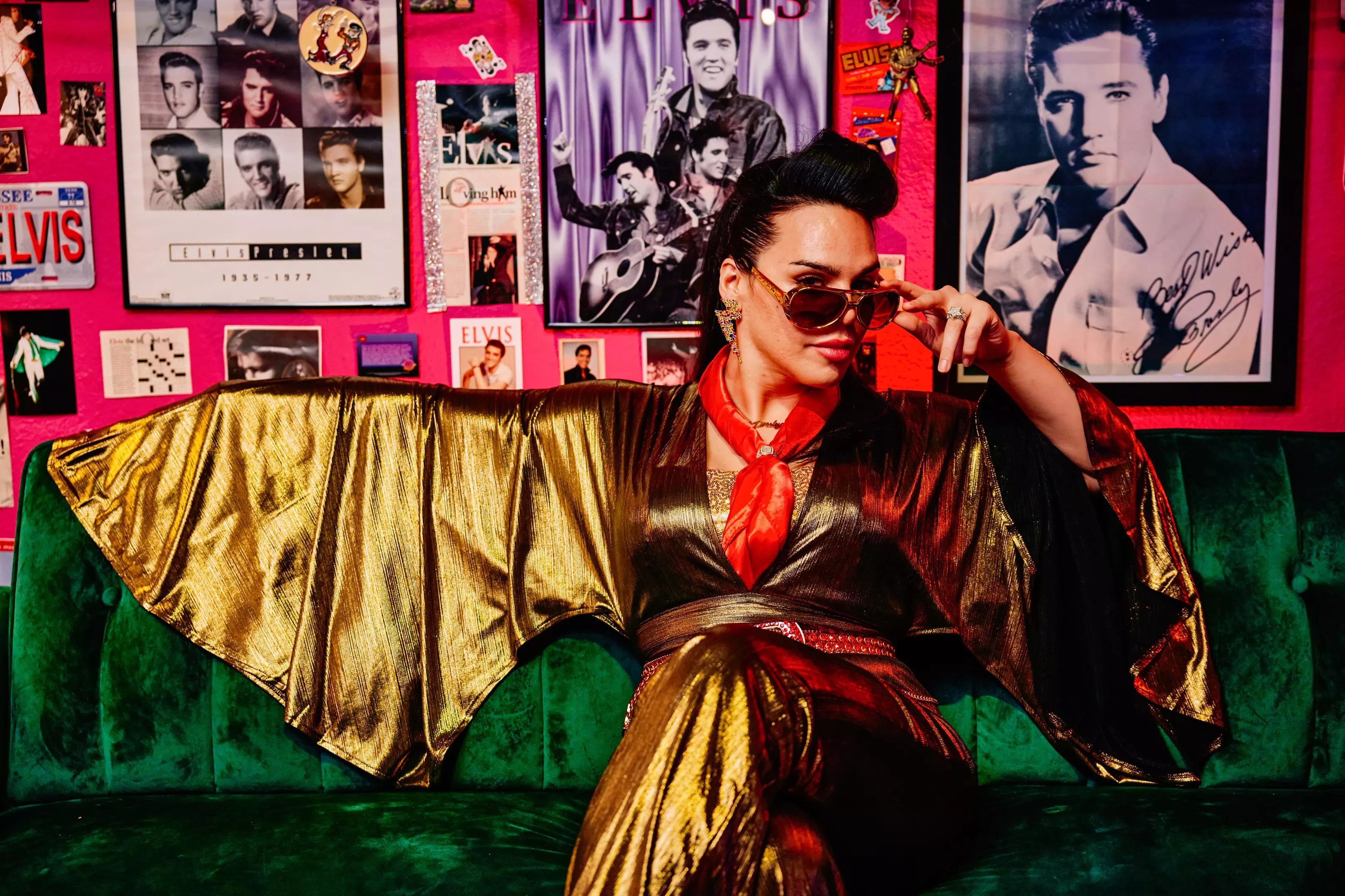 June Rave Romero seated on a couch in a gold jumpsuit and sunglasses