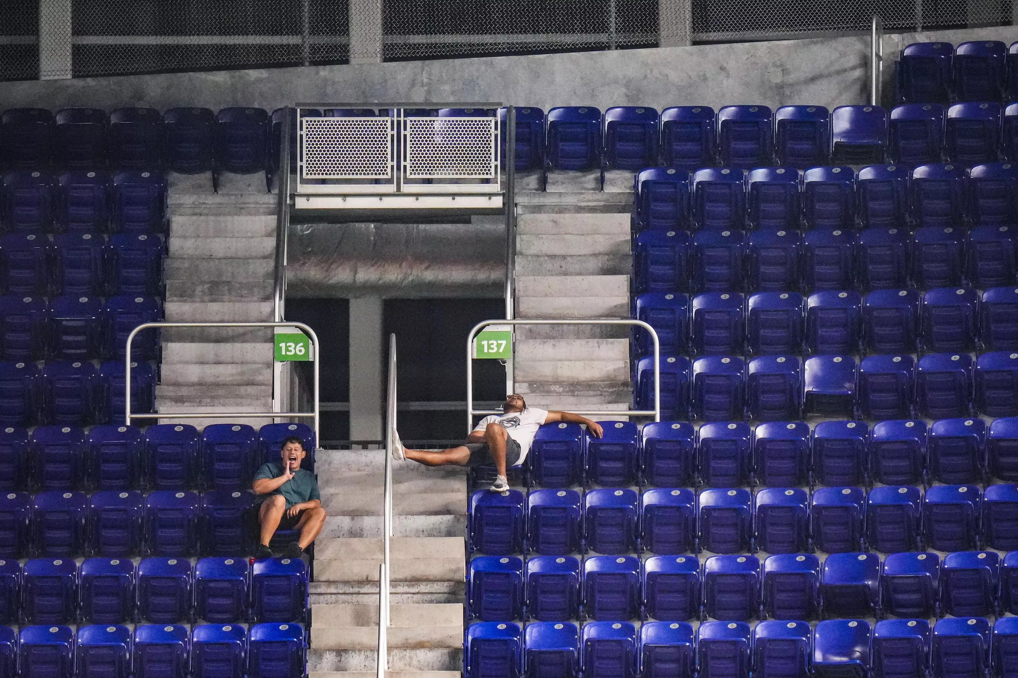 Two fans at the Miami Marlins' stadium in a sea of empty seats