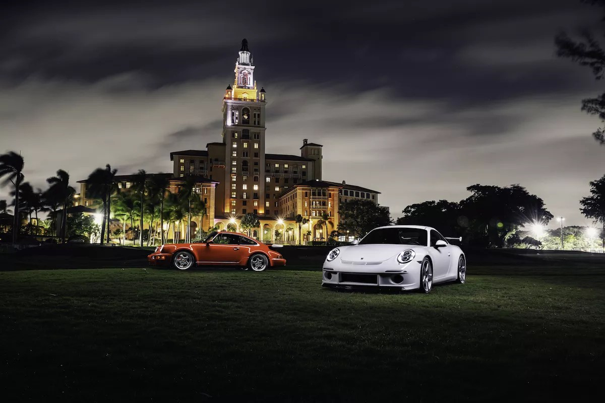 Sports cars in the night next to a hotel