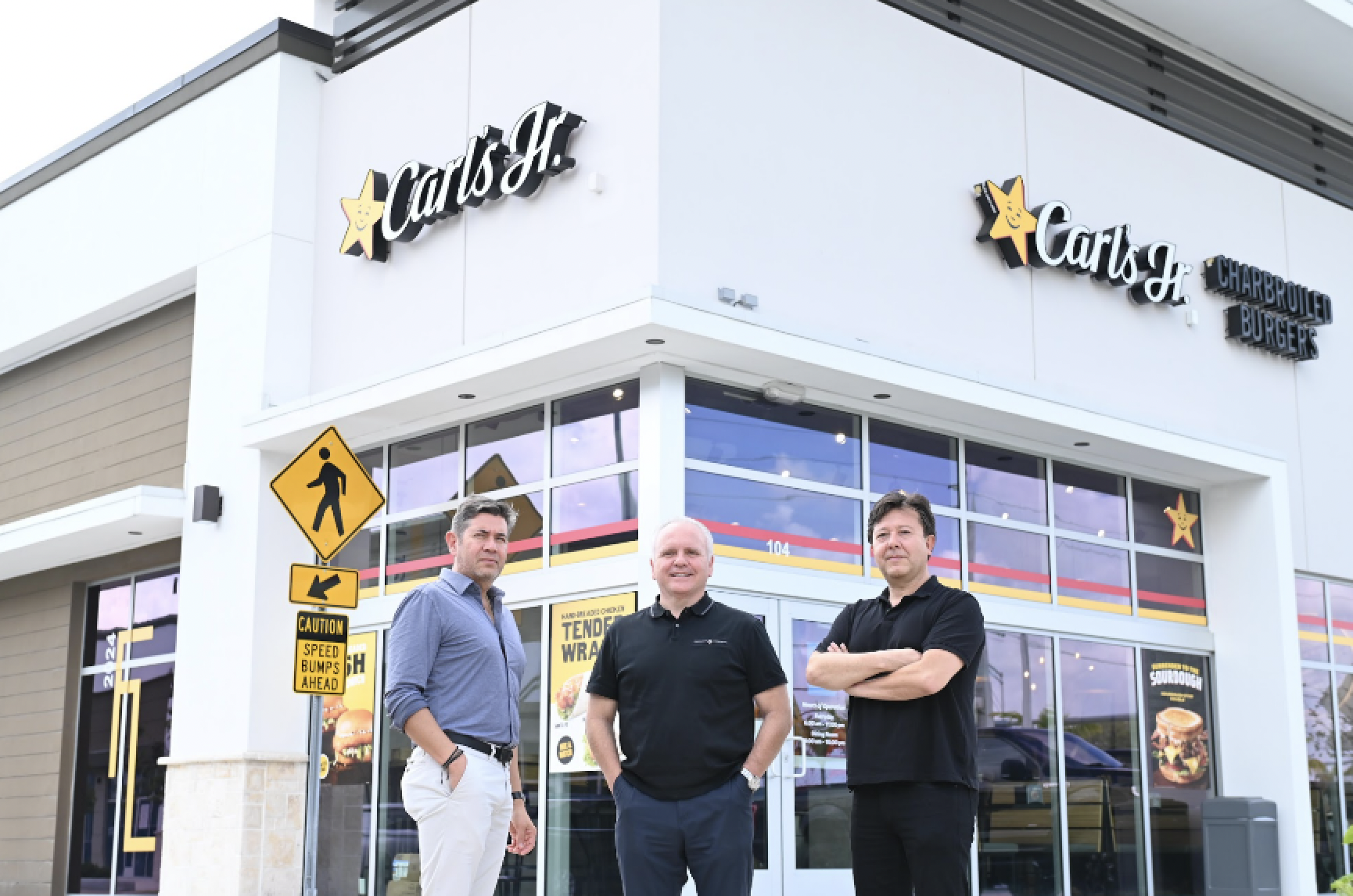 Three men in front of a building