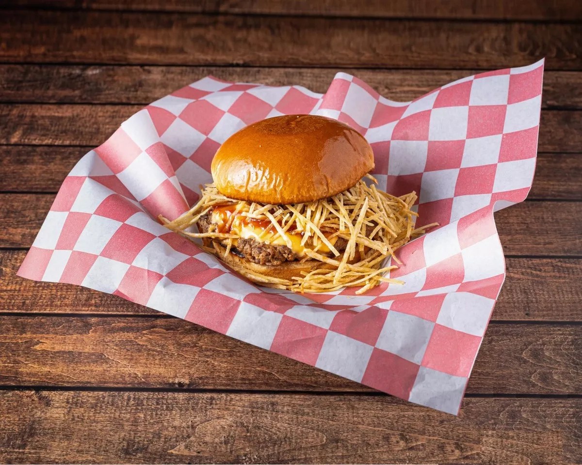 A burger with fries on red and white wax paper