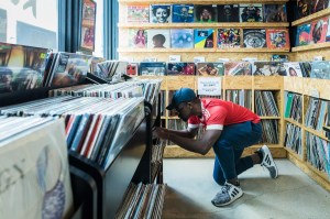 A man kneeling down while browsing for records