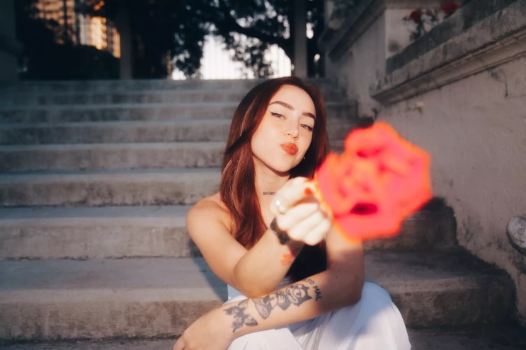 Nicki Nicole holding a flower toward the camera