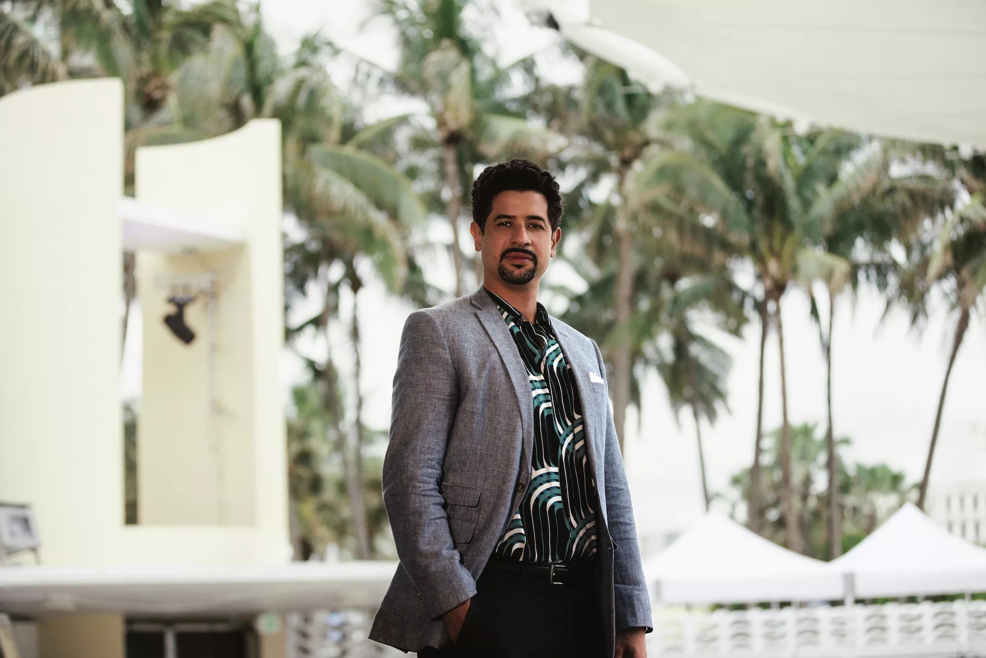 Adam Ganuza in a blazer in front of palm trees
