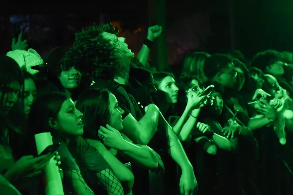 Fans at the front row of a 100 gecs concert bathed in green light
