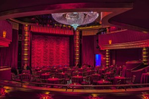 The interior of the Faena Theater with a red velvet curtain and huge crystal chandelier