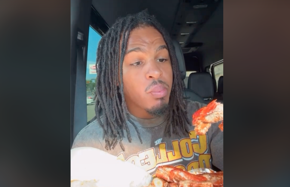 A man in a car holding ribs to eat