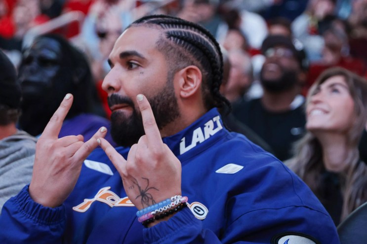 Closeup of rapper Drake throwing up hand signs at a Houston Rockets game.