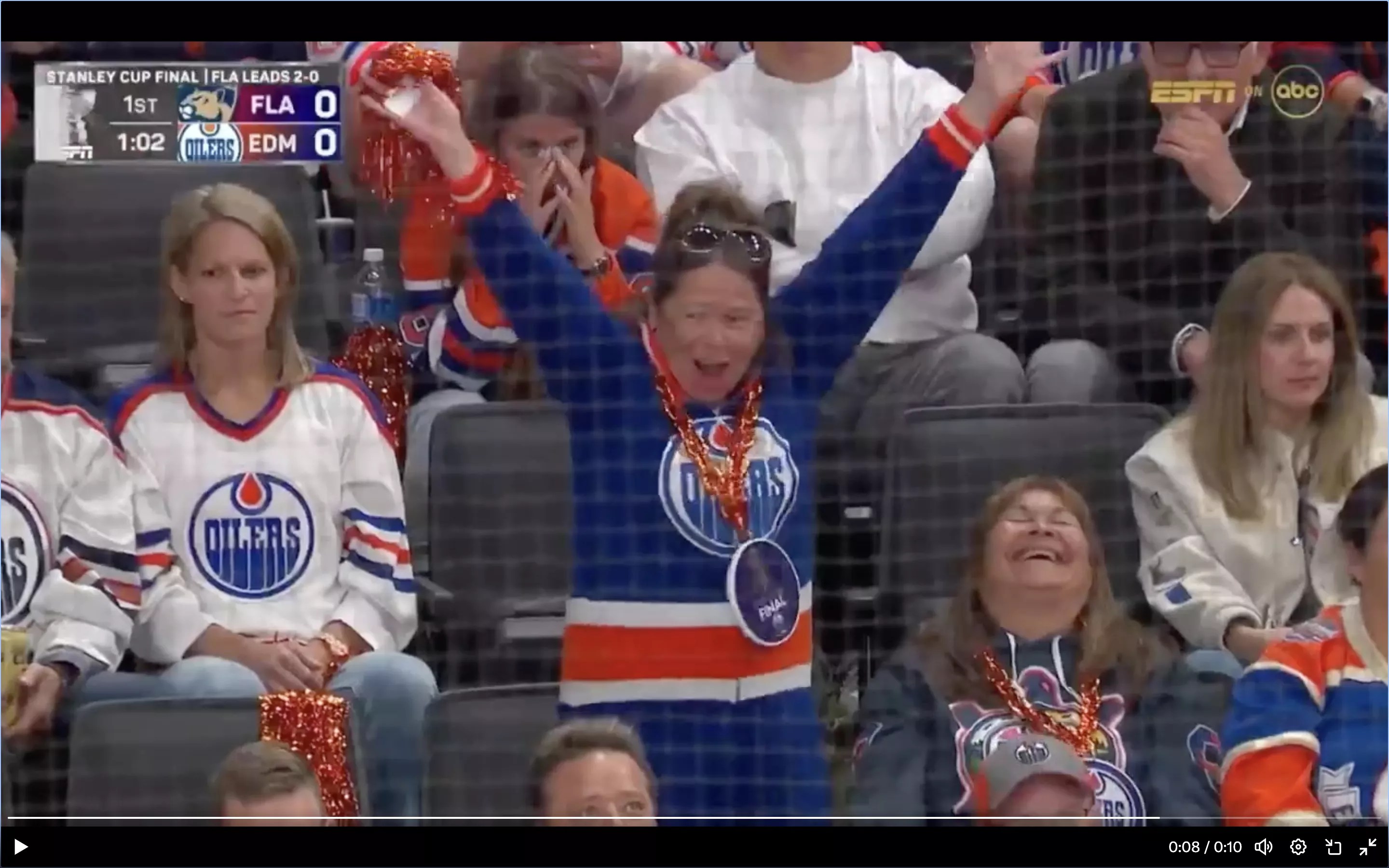 a woman in an Edmonton Oilers jersey appears to cheer a goal by the opposition Florida Panthers.