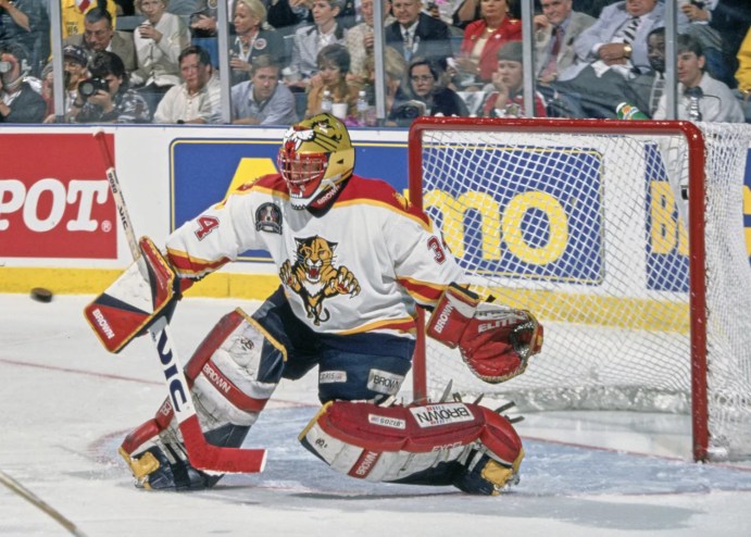 hockey goalie in home whites guards the net