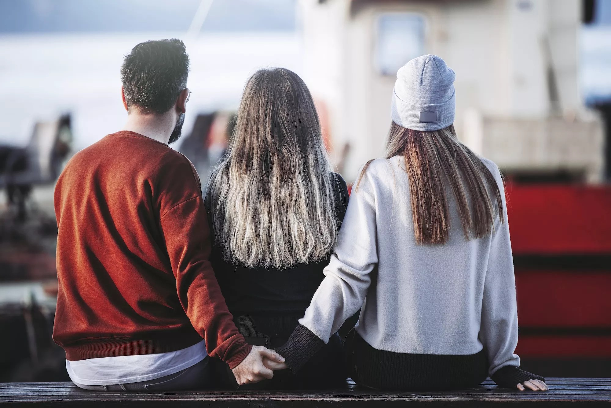 A man and woman holding hands behind another woman