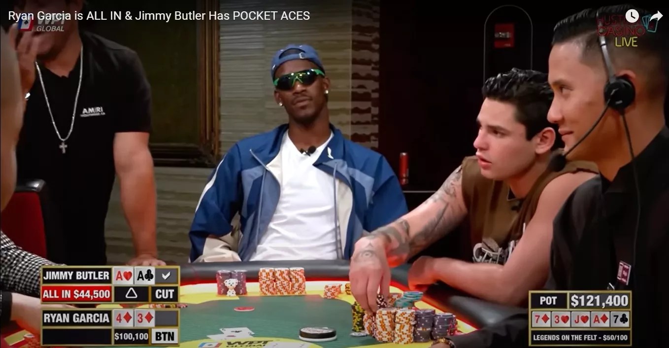 Jimmy Butler in sunglasses and backwards cap at a high stakes poker table
