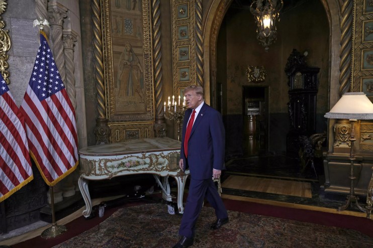 Trump makes his way into a room at his Mar-a-Lago resort, walking next to a piano and elaborate gold-colored fixtures