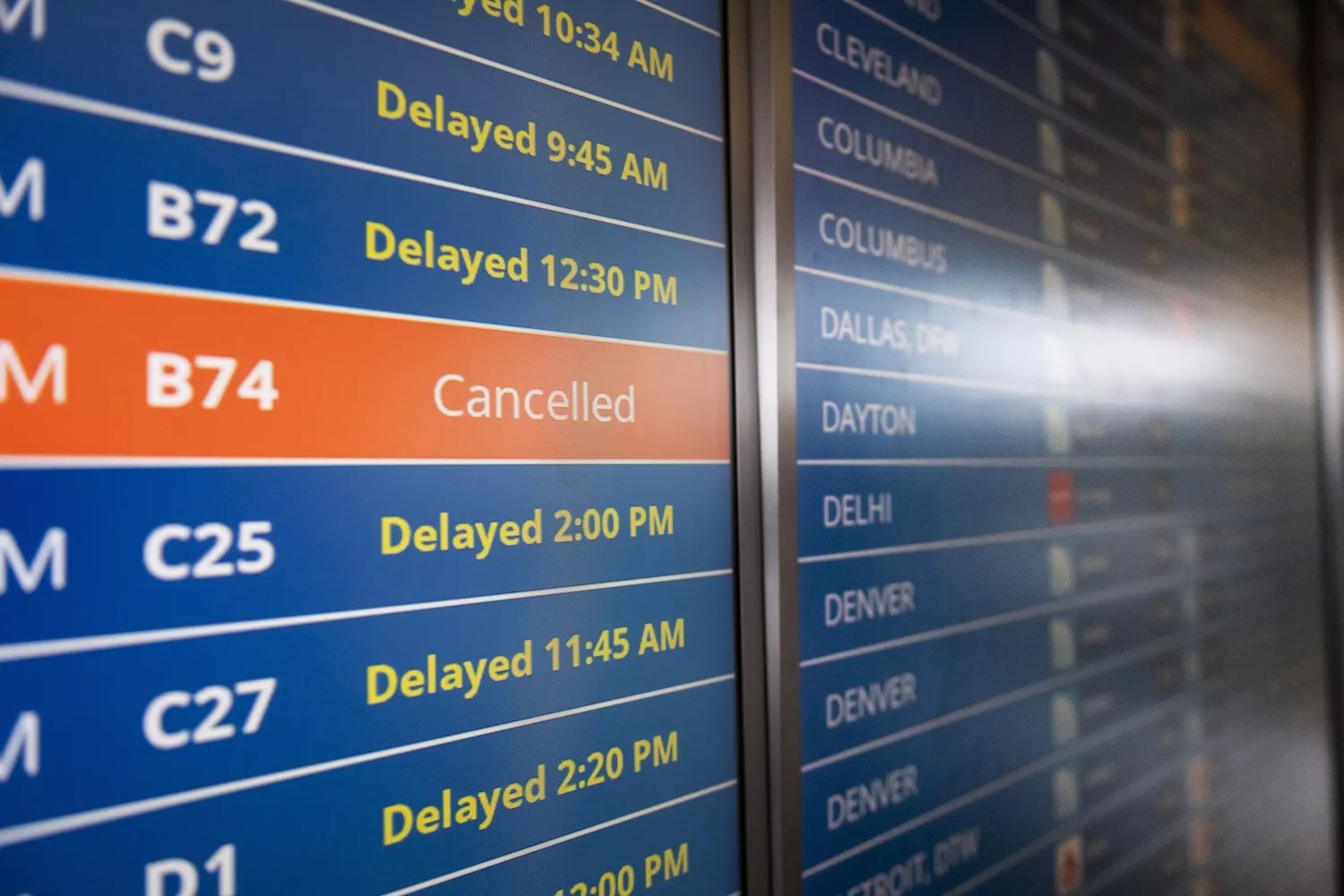 close-up photo of a board showing delays and cancellations at an airport
