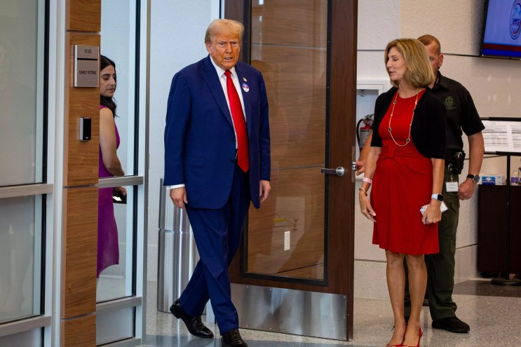 Trump walks into a local Palm Beach County polling place wearing signature suit and red tie
