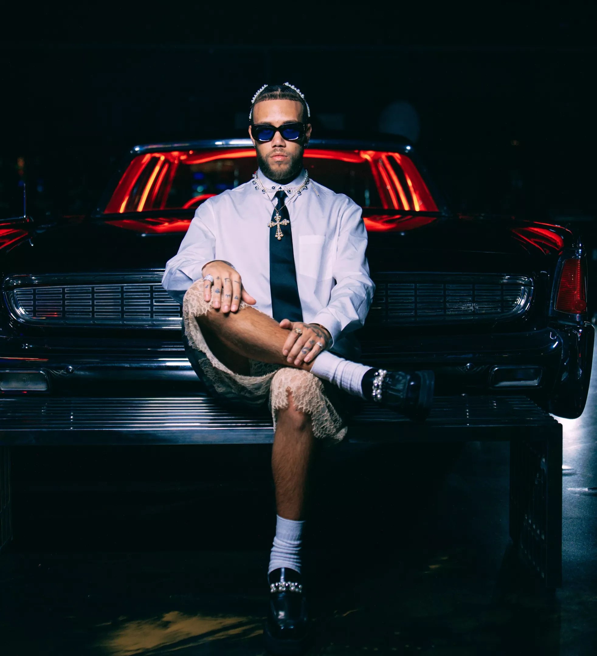 Portrait of Jhayco sitting in front of a car