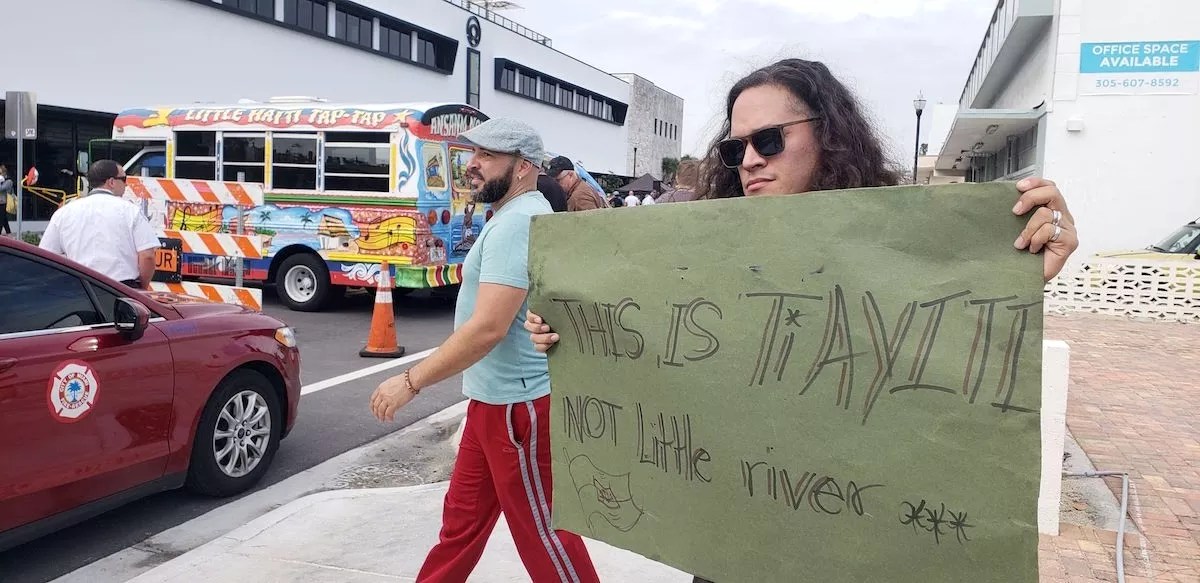 Man holding a signing reading "This is Ti Ayiti"