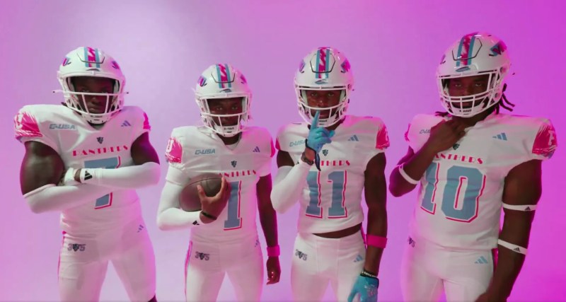 Four FIU football players wearing white Miami Vice-themed jerseys with pink and aqua accents, posing against a bright pink background
