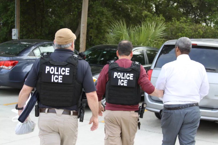 Two U.S. Immigration and Customs Enforcement (ICE) officers walking in the street.