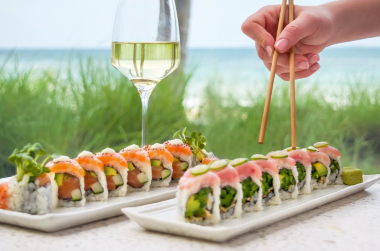 sushi, a glass of wine, and a hand holding chopsticks