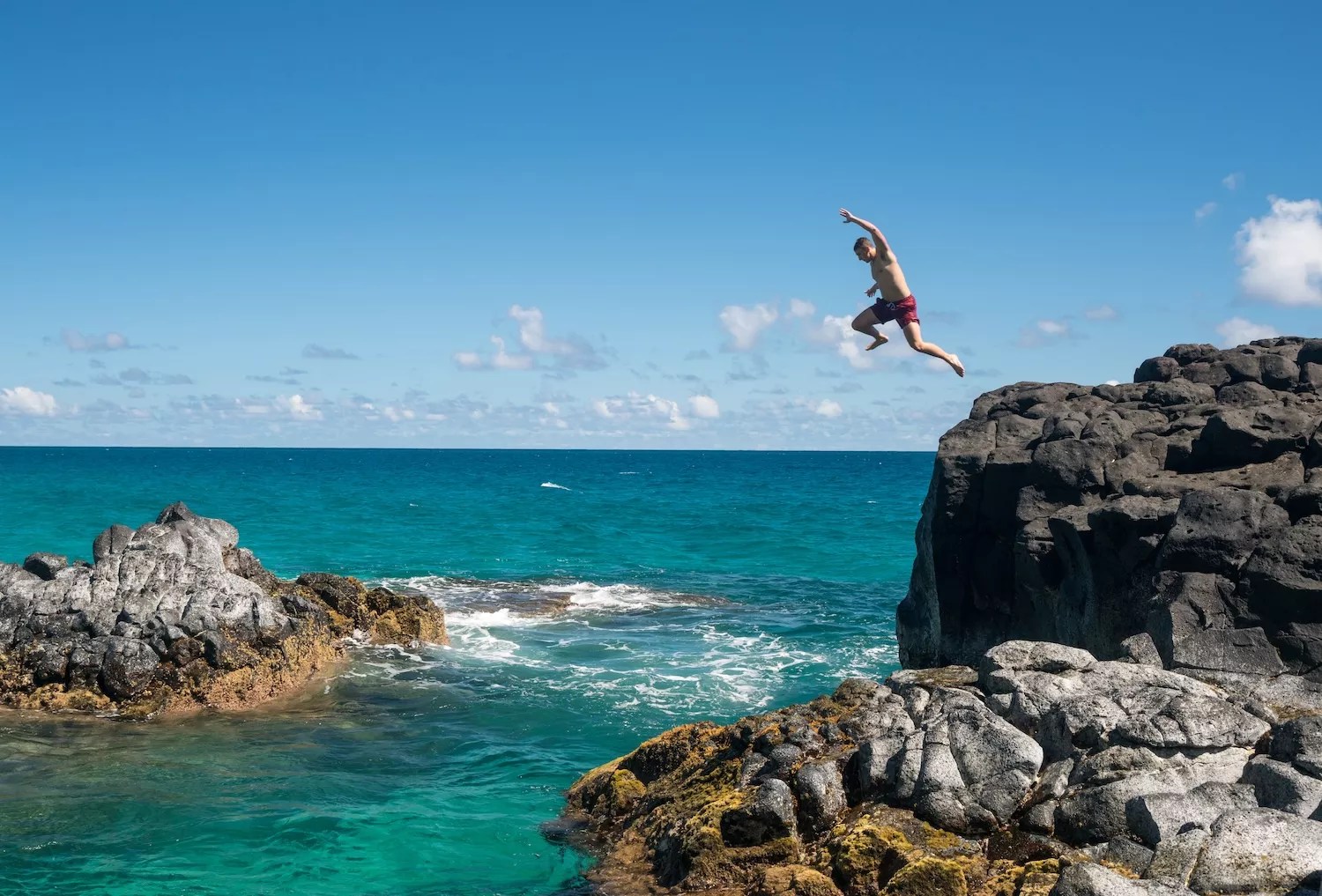color photo of guy leaping off a cliff into the sea