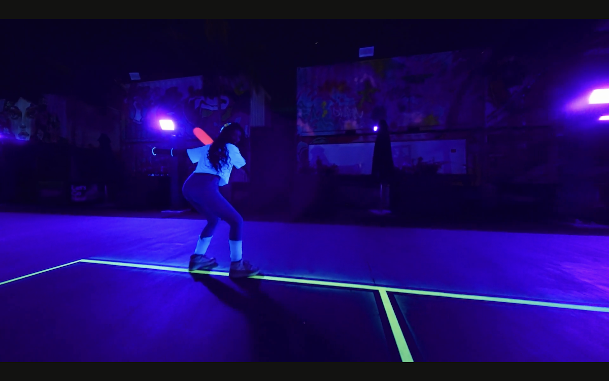 a person plays pickleball under blacklights