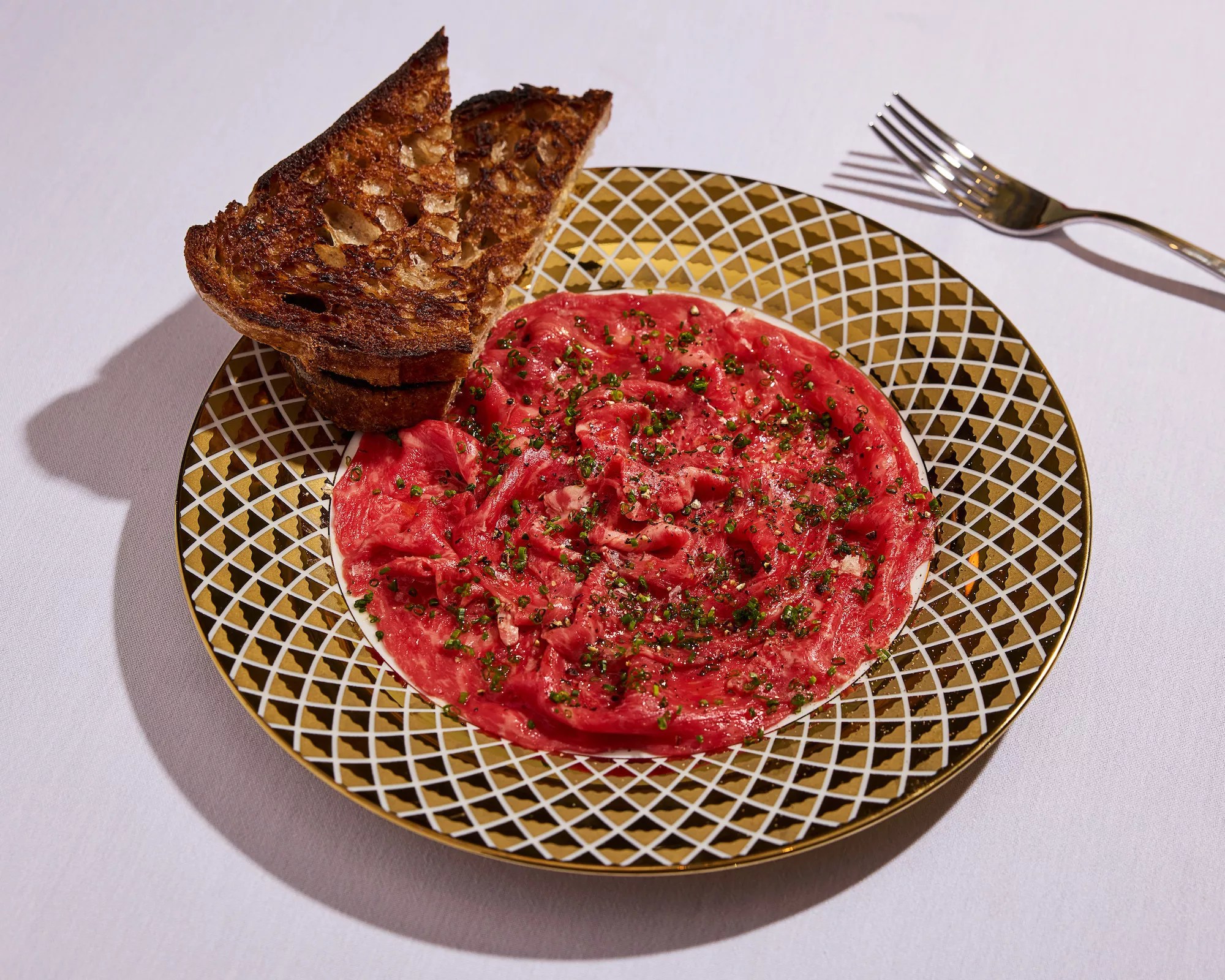 steak tartare in a ceramic serving dish with a side of toasted bread