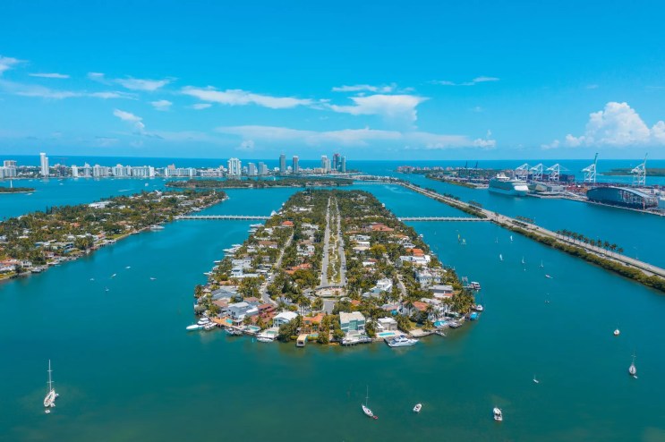 Color aerial view of Miami Beach Star Island, the Port of Miami, and surrounding waters on a nearly cloudless day.
