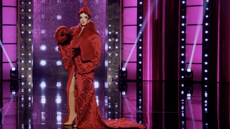 drag queen suzie toot wears a long red cocoon coat