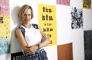 a woman stands in front of a wall of posters
