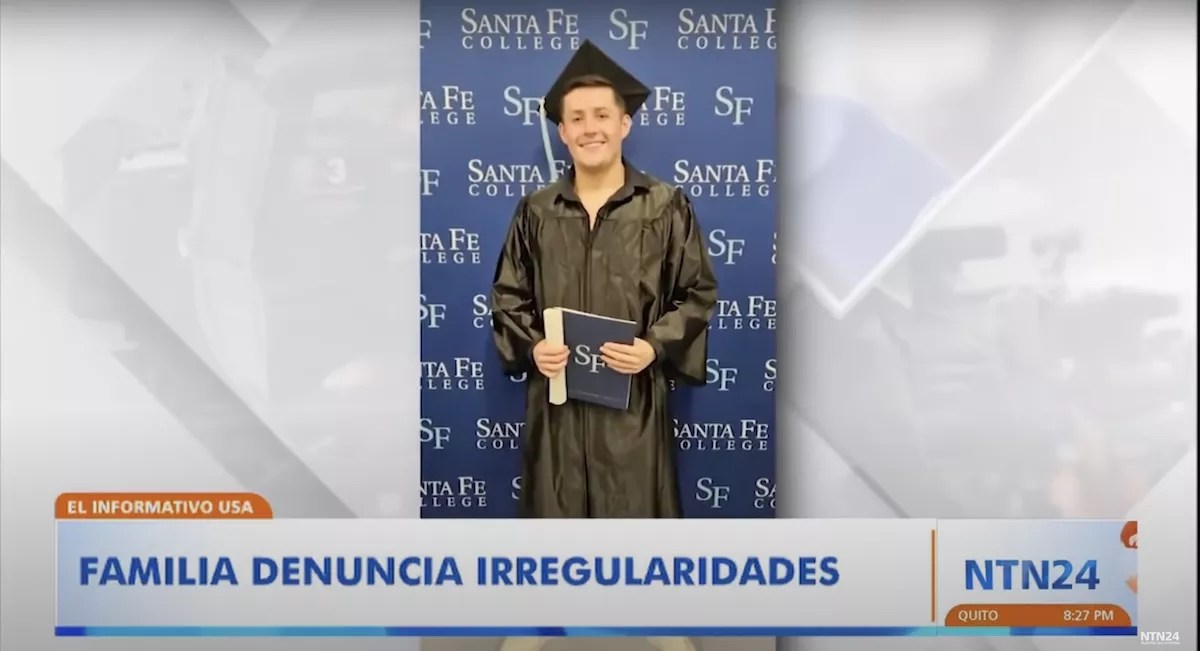 Photo of a young man in a black graduation cap and gown in front of a Santa Fe College banner.