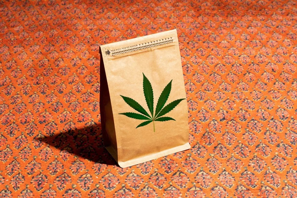 A brown paper bag with a marijuana symbol on it against an orange background