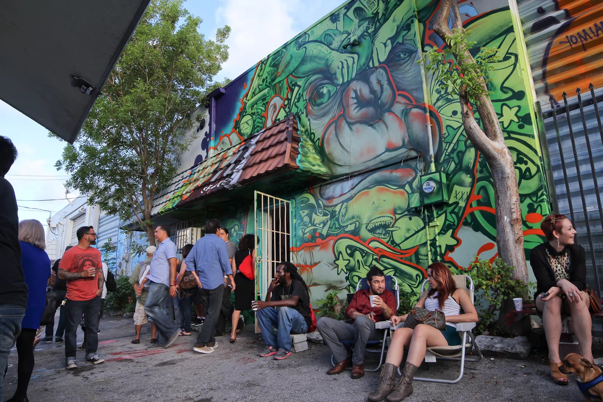 people sit and socialize outside a muralled building