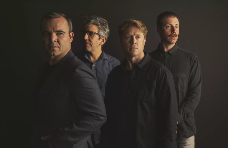 portrait of four band members standing side by side