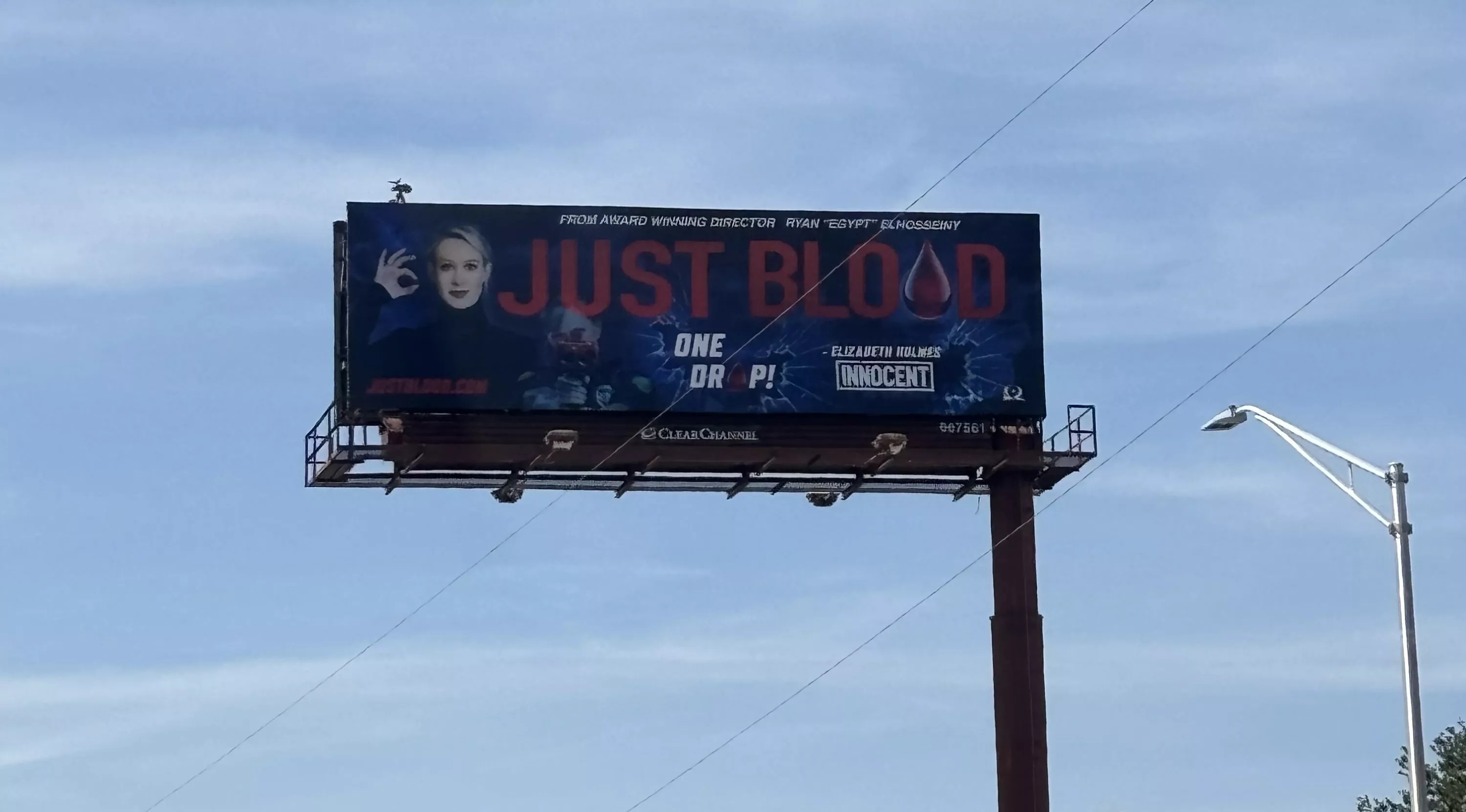 A billboard shows a blonde woman with the words "just blood" in bold print beside her.