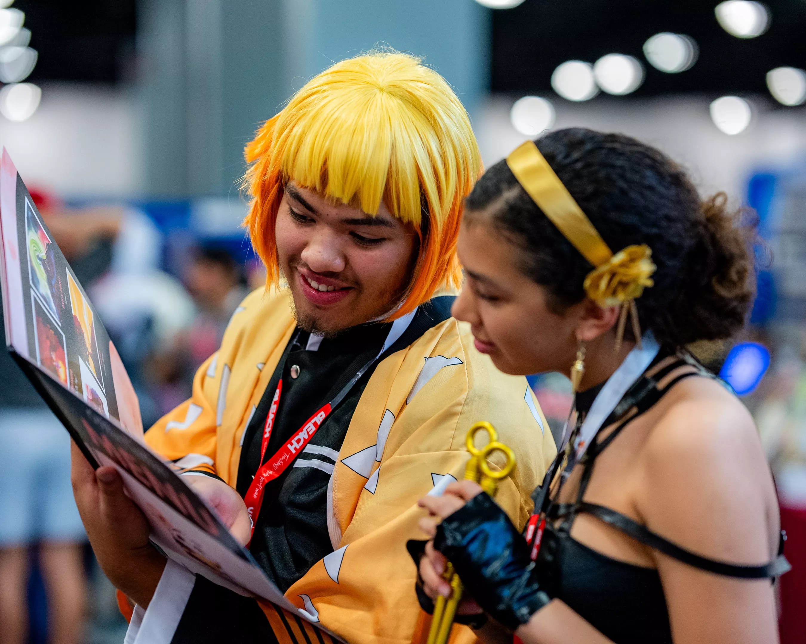 two young people in costume read a graphic novel at a cosplay convention
