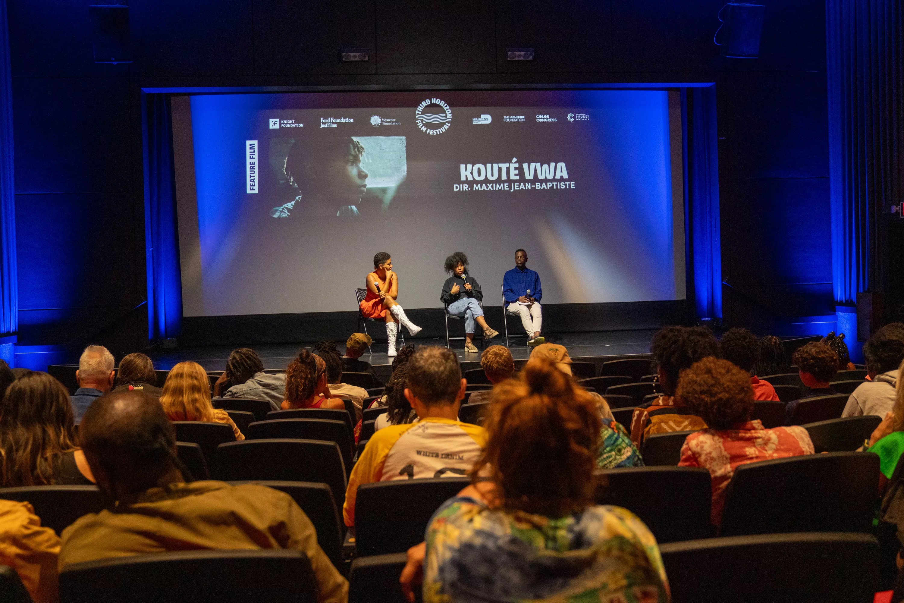 a panel sits on a stage in front of an audience after a movie screening