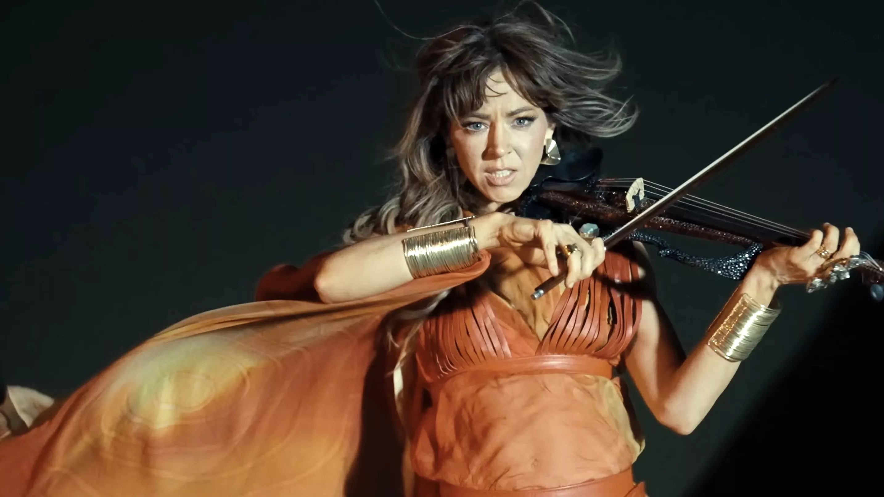 frame from a video showing a dramatic image of a woman playing a violin