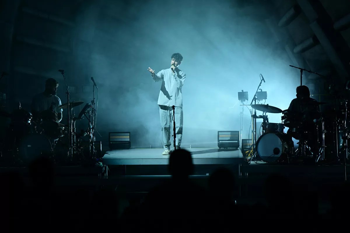 a band performing on an amphitheater stage under eerie, cloudy lighting