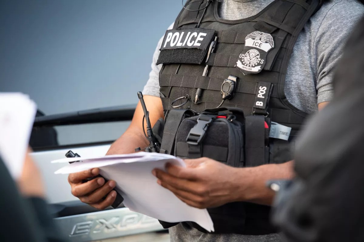 An ICE agent checks paperwork.